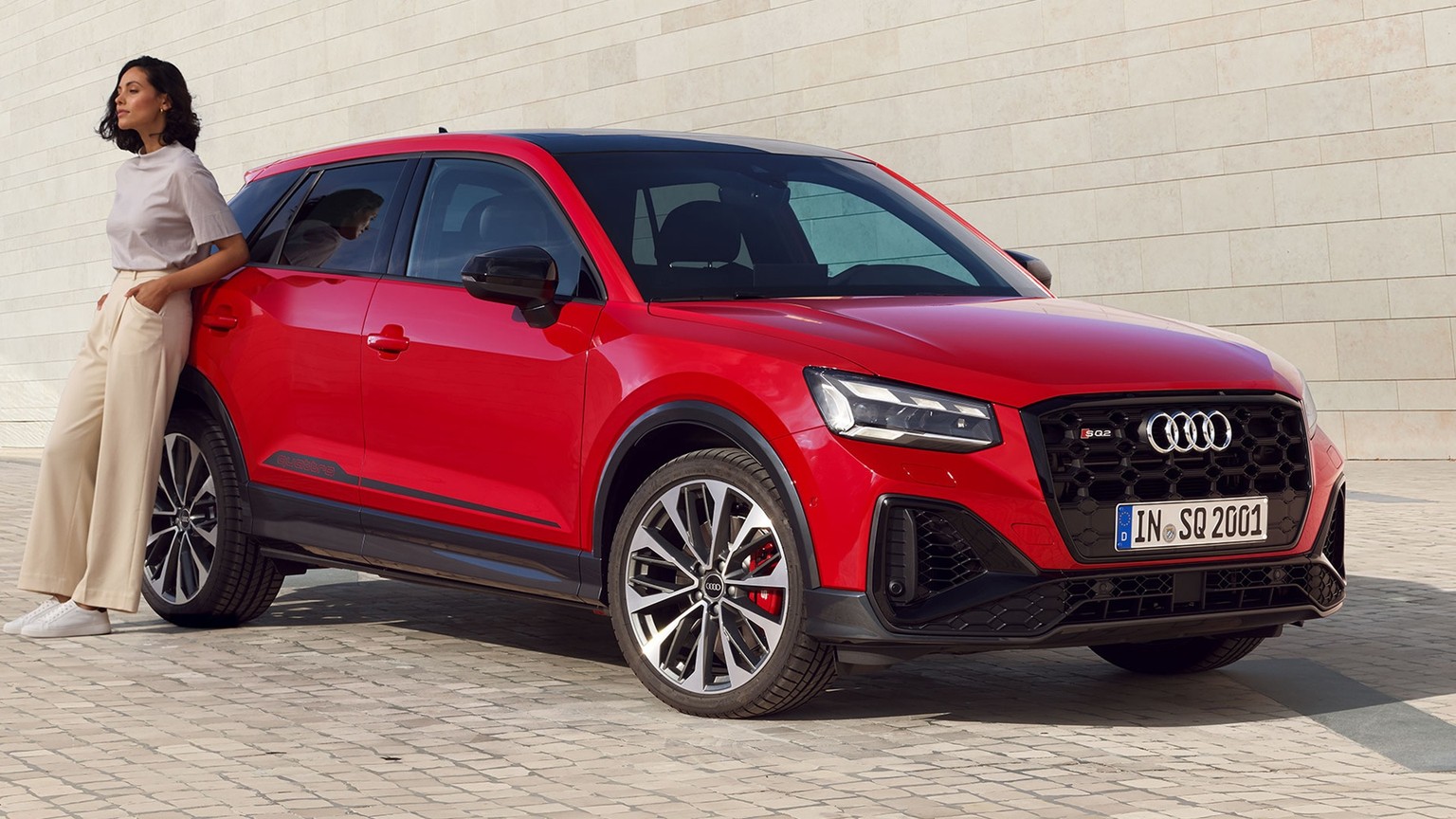 Front-side view of the Audi SQ2 with a woman leaning against the car.